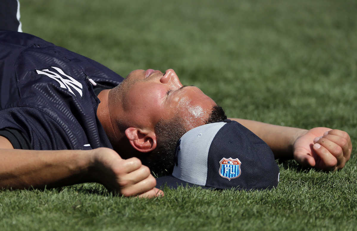 New York Yankees' Alex Rodriguez (13) lays on the infield with his cap by his side as he has his legs worked on at the start of batting practice before a spring training baseball game against the Boston Red Sox on Tuesday, March 15, 2016, in Fort Myers, Fla. (AP Photo/Tony Gutierrez)